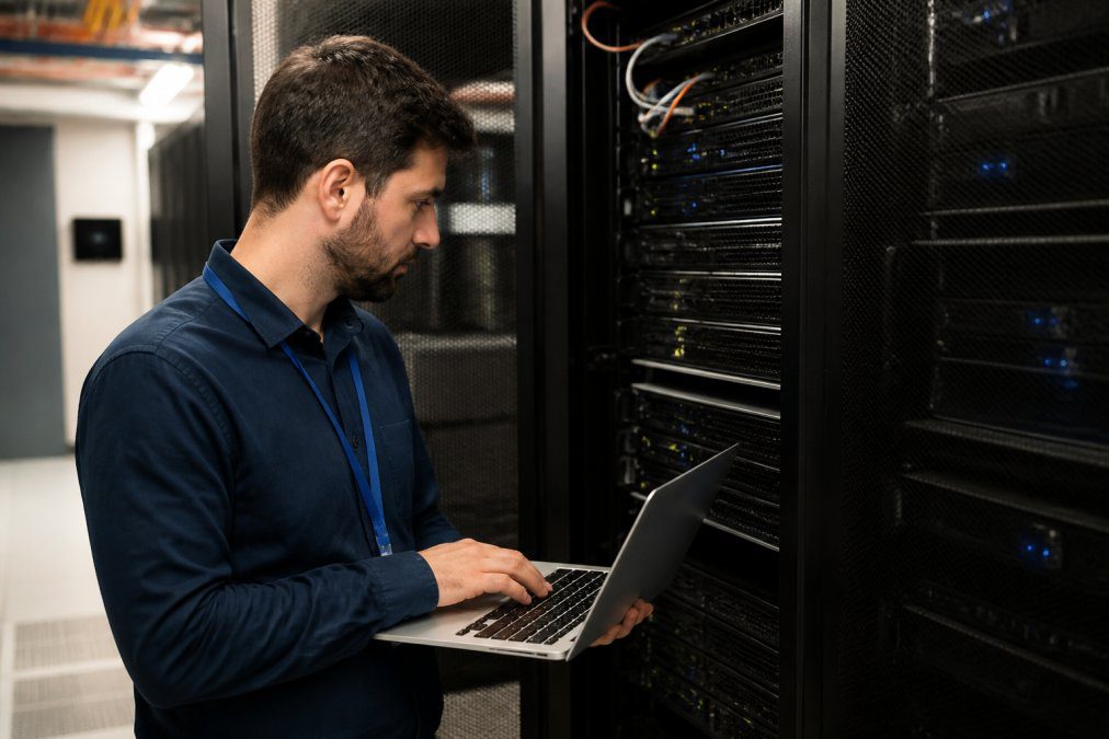 IT support professional monitoring website performance on multiple screens, with analytics and uptime dashboards visible
