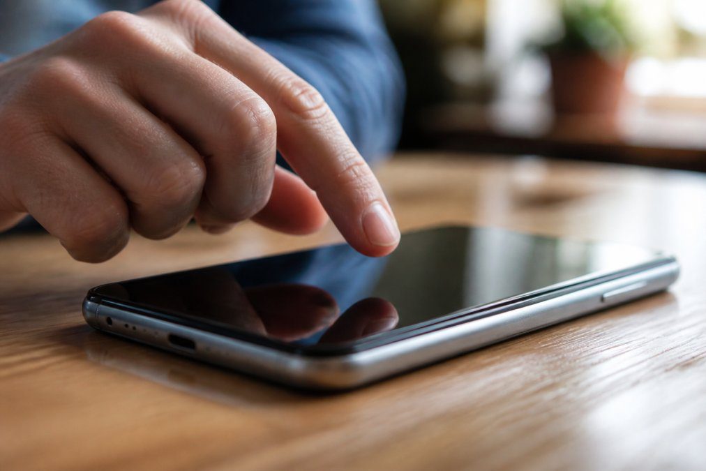 Close-up of a hand hovering over a prominent call-to-action button on a mobile device screen, with the button in sharp focus